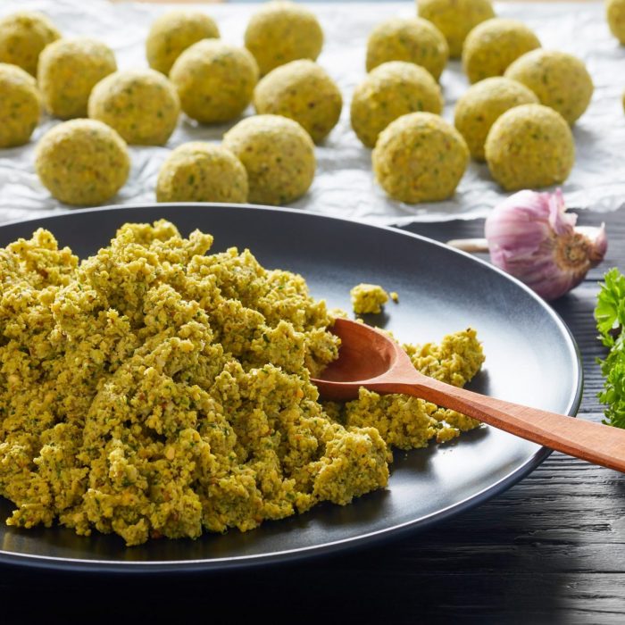 freshly ground chickpea mixed with greens and spices and raw falafel balls prepared to be fried or oven baked, middle eastern recipe, view from above, close-up